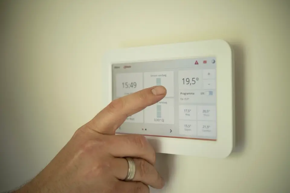Una mano ajusta la temperatura en un termostato digital de pared